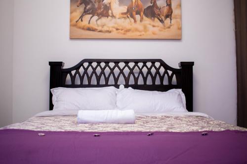 a bed with a purple blanket and a picture of horses at The Country Side Villa - Nanyuki in Nanyuki