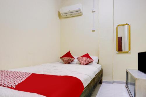 OYO 91423 Ringin Pitu 1 Syariah في Jodoh: غرفة نوم بسرير احمر وبيض مع مرآة