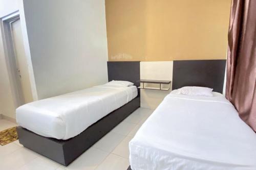 two beds in a hotel room with white sheets at RedDoorz Syariah @ Jalan Jendral Sudirman Pekanbaru in Pekanbaru