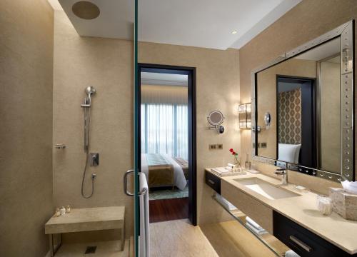 a bathroom with a shower and a sink and a mirror at The Leela Gandhinagar in Gandhinagar