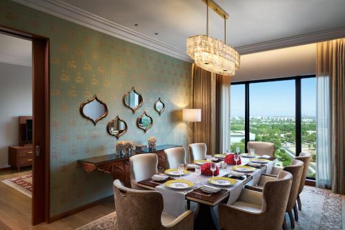 a dining room with a table and chairs and a chandelier at The Leela Gandhinagar in Gandhinagar