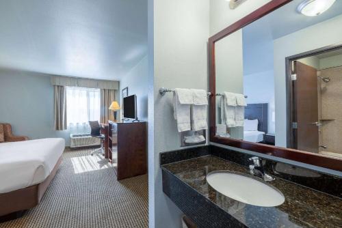 a hotel room with a bed and a bathroom with a sink at Baymont by Wyndham Rapid City in Rapid City