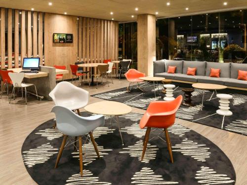 a lobby with tables and chairs and a laptop at ibis Campo Grande in Campo Grande