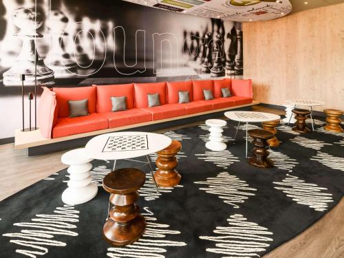 un soggiorno con divano rosso e tavoli di ibis Campo Grande a Campo Grande