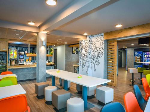 a dining room with a table and colorful chairs at ibis budget Coutances in Coutances
