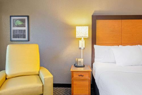 a hotel room with a bed and a yellow chair at La Quinta by Wyndham New Orleans Airport in Kenner