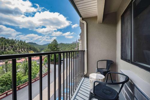 a balcony with two chairs and a view at Baymont by Wyndham Keystone Near Mt. Rushmore in Keystone