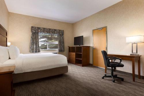 a hotel room with a bed and a desk and a chair at Days Inn & Suites by Wyndham Brooks in Brooks