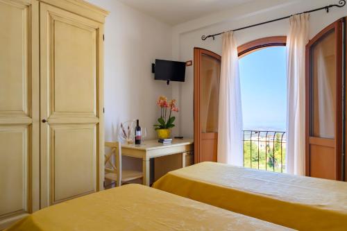 a hotel room with two beds and a window at Hotel Marie Claire in Lanusei