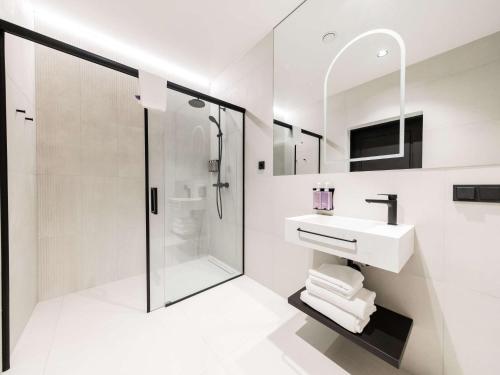 a white bathroom with a sink and a shower at Tribe Riga City Center in Rīga