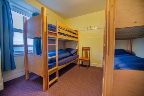 ブロードフォードにあるBroadford Youth Hostelの二段ベッド2組とはしごが備わる二段ベッド付きの客室です。
