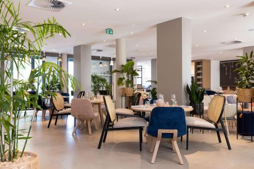 un restaurant avec des tables, des chaises et des plantes dans l'établissement Hilton Garden Inn Tours Centre, France, à Tours