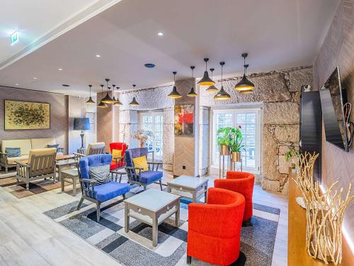 a lobby with chairs and tables and a stone wall at ibis Styles Chaves in Chaves