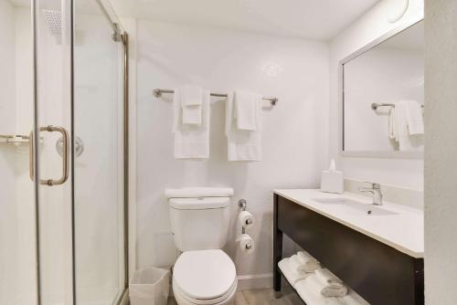 a white bathroom with a toilet and a sink at Chateau Mar Golf Resort, Trademark Collection by Wyndham in Lauderhill