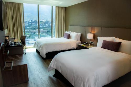 a hotel room with two beds and a large window at Camino Real Fashion Drive Monterrey in Monterrey