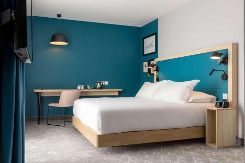 a bedroom with a blue wall and a bed and a desk at Hampton by Hilton Tours Centre, France in Tours