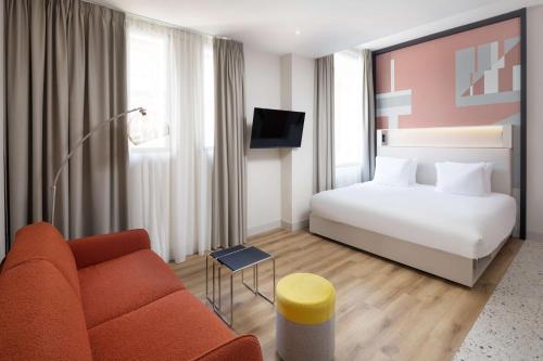 a hotel room with a bed and a couch at Motto By Hilton Rotterdam Blaak in Rotterdam