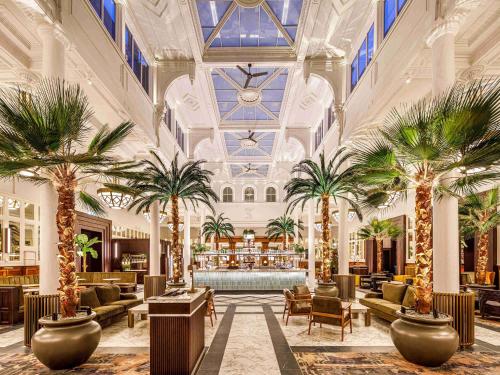a hotel lobby with palm trees and a bar at The Municipal Hotel Liverpool - MGallery in Liverpool