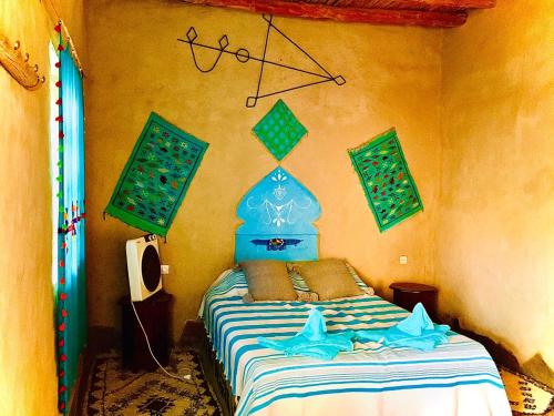 Schlafzimmer mit einem Bett mit blauem Kopfteil in der Unterkunft Dar Oasis Moringa in Merzane