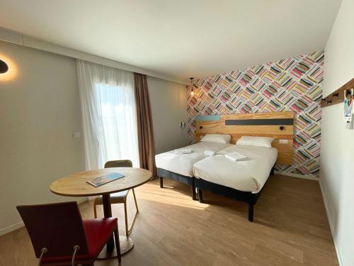 カステにあるgreet hotel Castets Coeur des Landesのベッド、テーブル、テーブルシックスシックスが備わるホテルルームです。