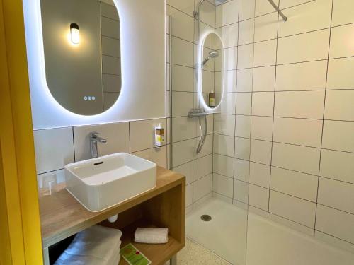 a white bathroom with a sink and a shower at greet hotel Castets Coeur des Landes in Castets