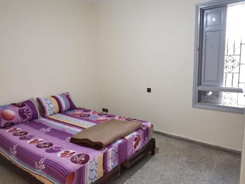 fioletowe łóżko w pokoju z oknem w obiekcie Appartement 70m 2 à 2 min de la gare de Safi w mieście Safi