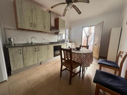 uma cozinha com uma mesa com cadeiras e uma ventoinha de tecto em Alojamiento rural Huerta Mandre em Cuevas del Becerro