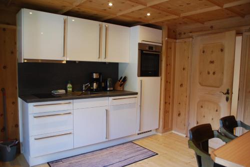 a kitchen with white cabinets and a white refrigerator at Haus Galgenul in Sankt Gallenkirch