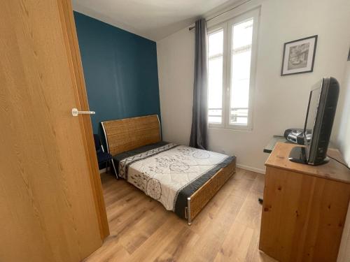 Dormitorio pequeño con cama y TV en Rooftop vue sur le stade de France, en Saint-Denis