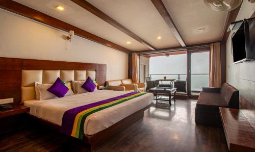 a bedroom with a bed and a television and a couch at Treebo Tryst Queen Of Hills Near Mall Road in Mussoorie