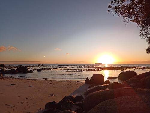 a sunset on a beach with rocks in the water at Bonne Esperance, Simon's Town in Simonʼs Town