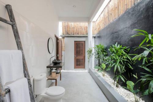 La salle de bains est pourvue de toilettes et de plantes. dans l'établissement AMAZING 3 BDR Canggu Villa in ULTIMATE location, à Canggu