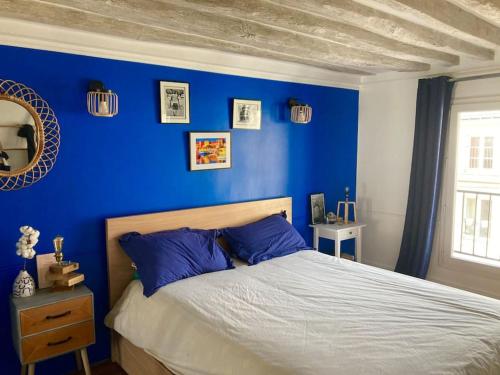 1 dormitorio con paredes azules y 1 cama con almohadas azules en Charming 3F apartment in Paris' heart (61 sqm) en París