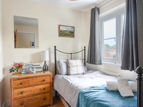 a bedroom with a bed and a dresser and a window at Rivermead in Seaton