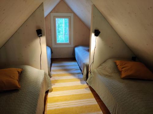 a attic room with three beds and a window at Yksipuinen in Ähtäri