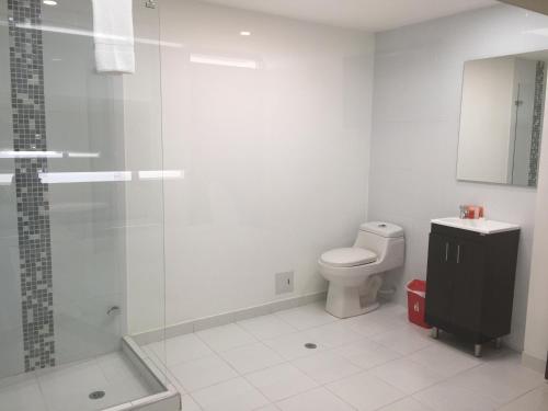 a white bathroom with a shower and a toilet at Hotel Metro 26 in Bogotá