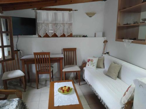 a living room with a white couch and a table at Panthea Cottage in Stavroupoli