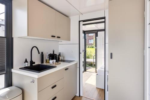 泽沃德Cosy tiny houseboats near beach and restaurants by Weltevreden Experience的带白色橱柜和水槽的厨房