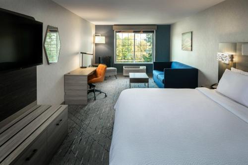 a hotel room with a bed and a living room at Holiday Inn Express Corvallis-On the River by IHG in Corvallis