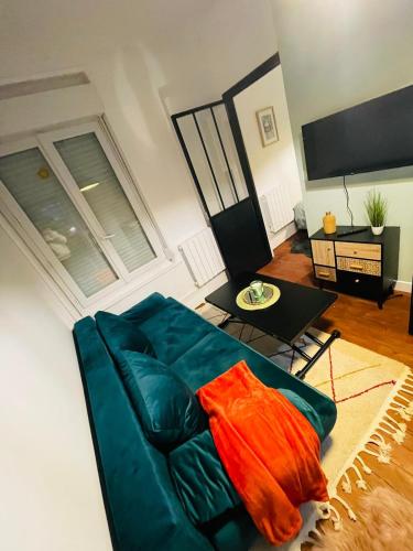 un salon avec un canapé bleu et une table dans l'établissement Le Vasco T avec salle de sport, à Amiens