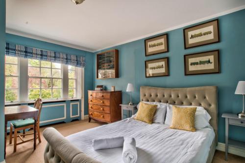 a bedroom with blue walls and a bed and a desk at Abbey House by Group Retreats in Saffron Walden