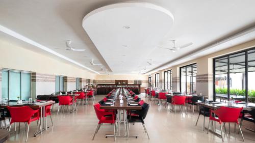 a dining room with tables and red chairs at Hotel Sonar Bangla Mandarmoni in Mandarmoni