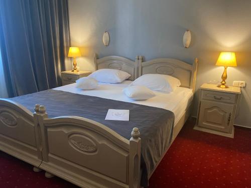 a bedroom with a large white bed with two lamps at Hotel Brilliant Meseș in Zalău