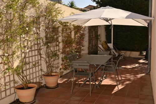 a table and chairs under an umbrella on a patio at Bastide le Petit Clos - les 2 Gîtes in Perpignan