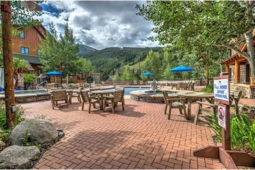 eine Terrasse mit Tischen und Stühlen neben einem Pool in der Unterkunft River Run Village Condominiums in Keystone