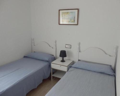 2 Einzelbetten in einem Zimmer mit einer Lampe auf einem Tisch in der Unterkunft Taravilla 26 2 dormitorios 1 in Puerto de Mazarrón