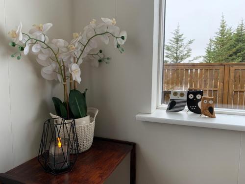 eine Vase mit Blumen auf einem Tisch neben einem Fenster in der Unterkunft Skeiðvellir Villa in Hella