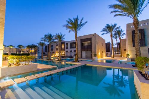 a swimming pool with palm trees and buildings at Nayah Stays, Ground terraces Studio in Hurghada