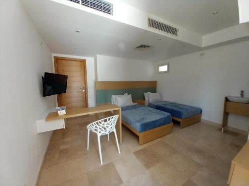 a bedroom with two beds and a desk and a television at Nayah Stays, Ground terraces Studio in Hurghada