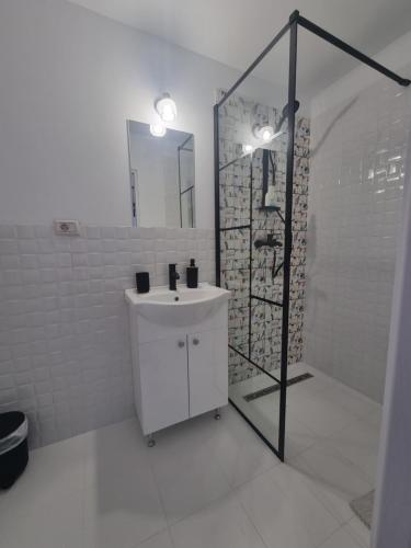 a white bathroom with a sink and a shower at Andreea's place in Braşov